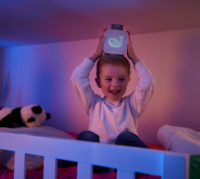 Child in bed holding Yoto Player