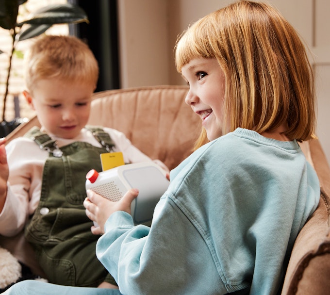Two children playing with a Yoto Player 3rd Generation