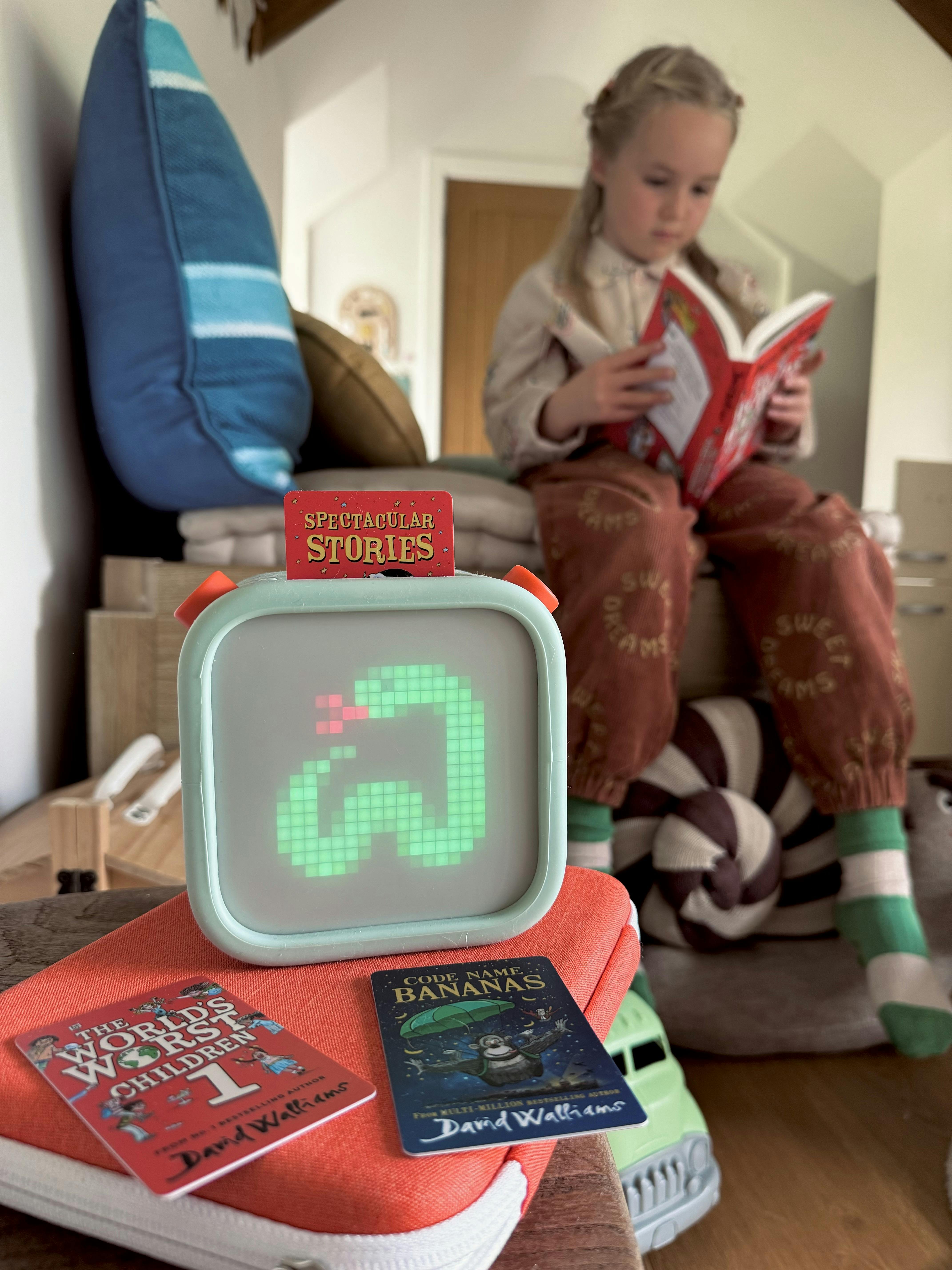 Child reading a book whilst listening to Yoto Player