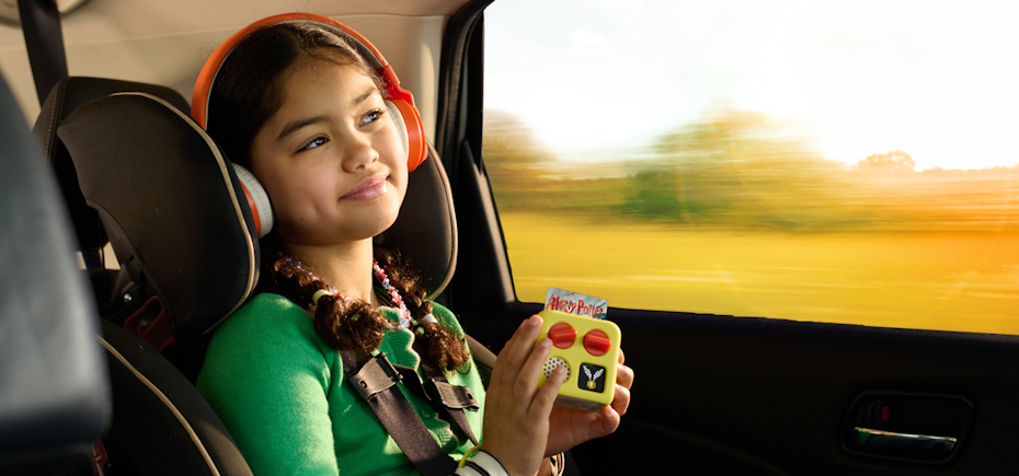 Child in a car seat using a yoto mini with headphones