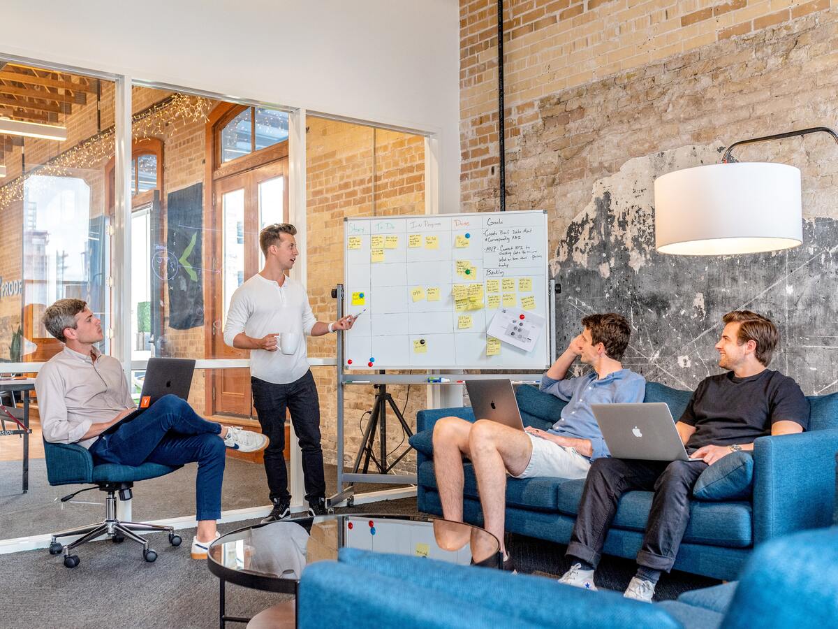 Three men listen as their team member presents ideas