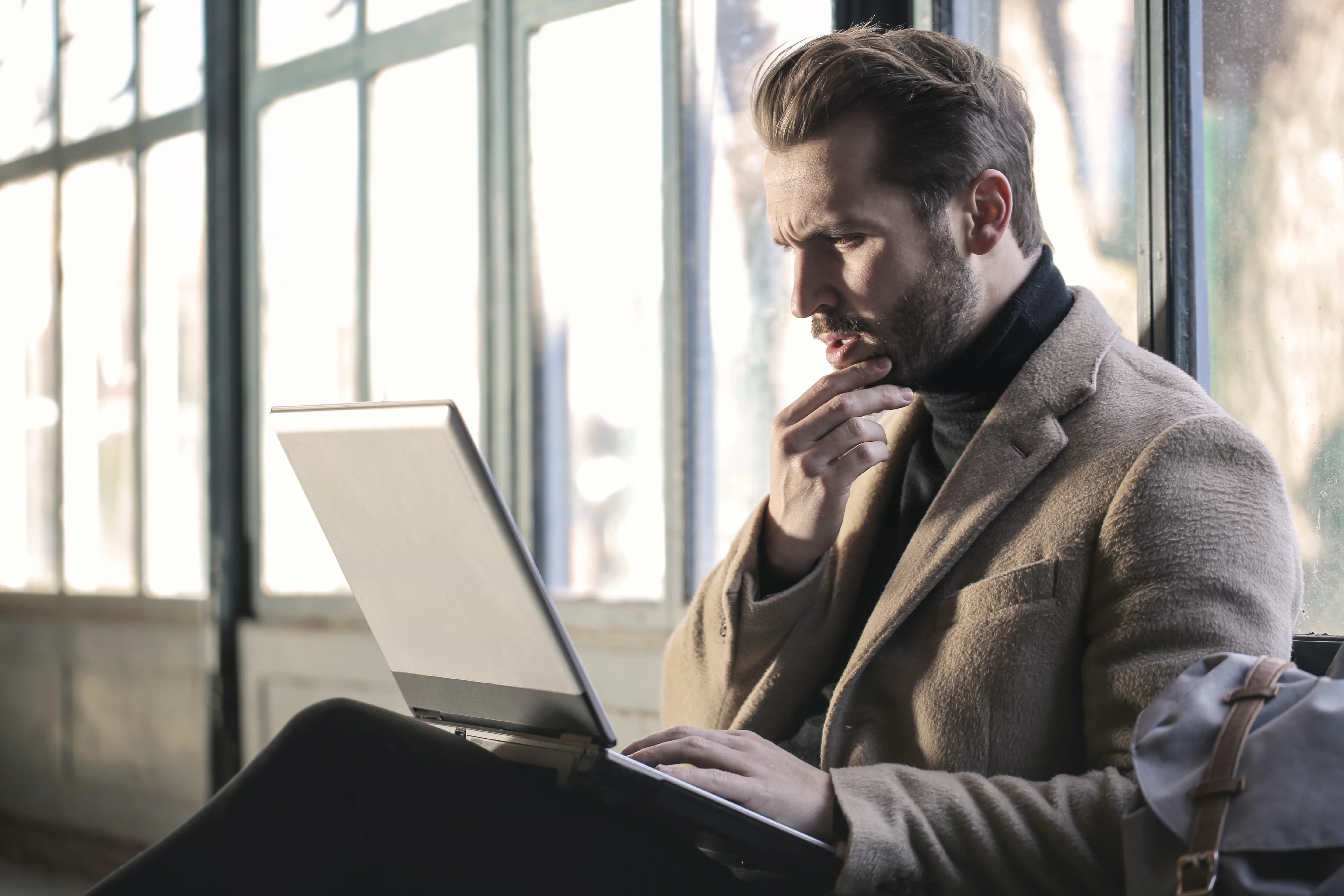 A man contemplates in front of his laptop