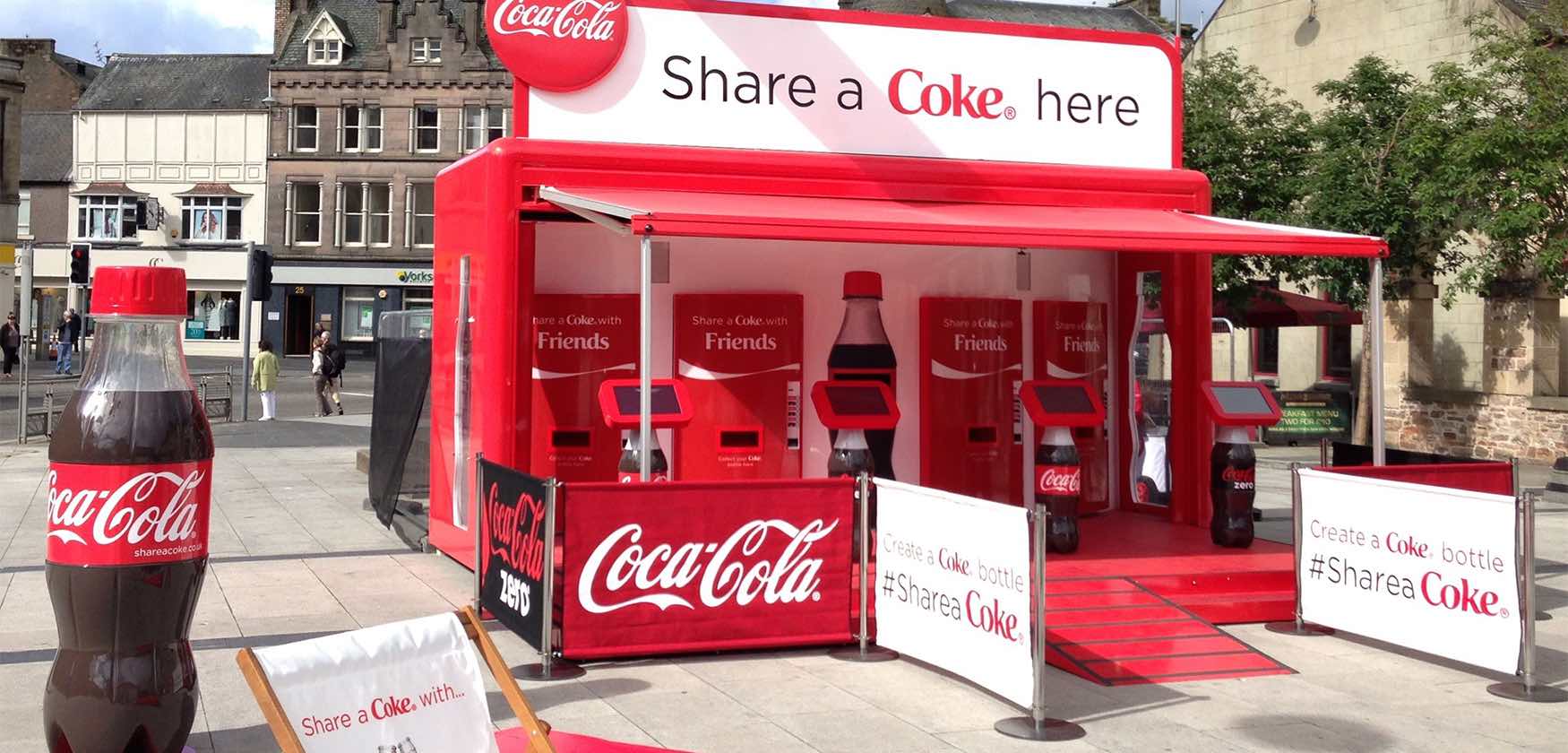 A red pop-up shop with Coca-cola vending machines that can print names on the bottles