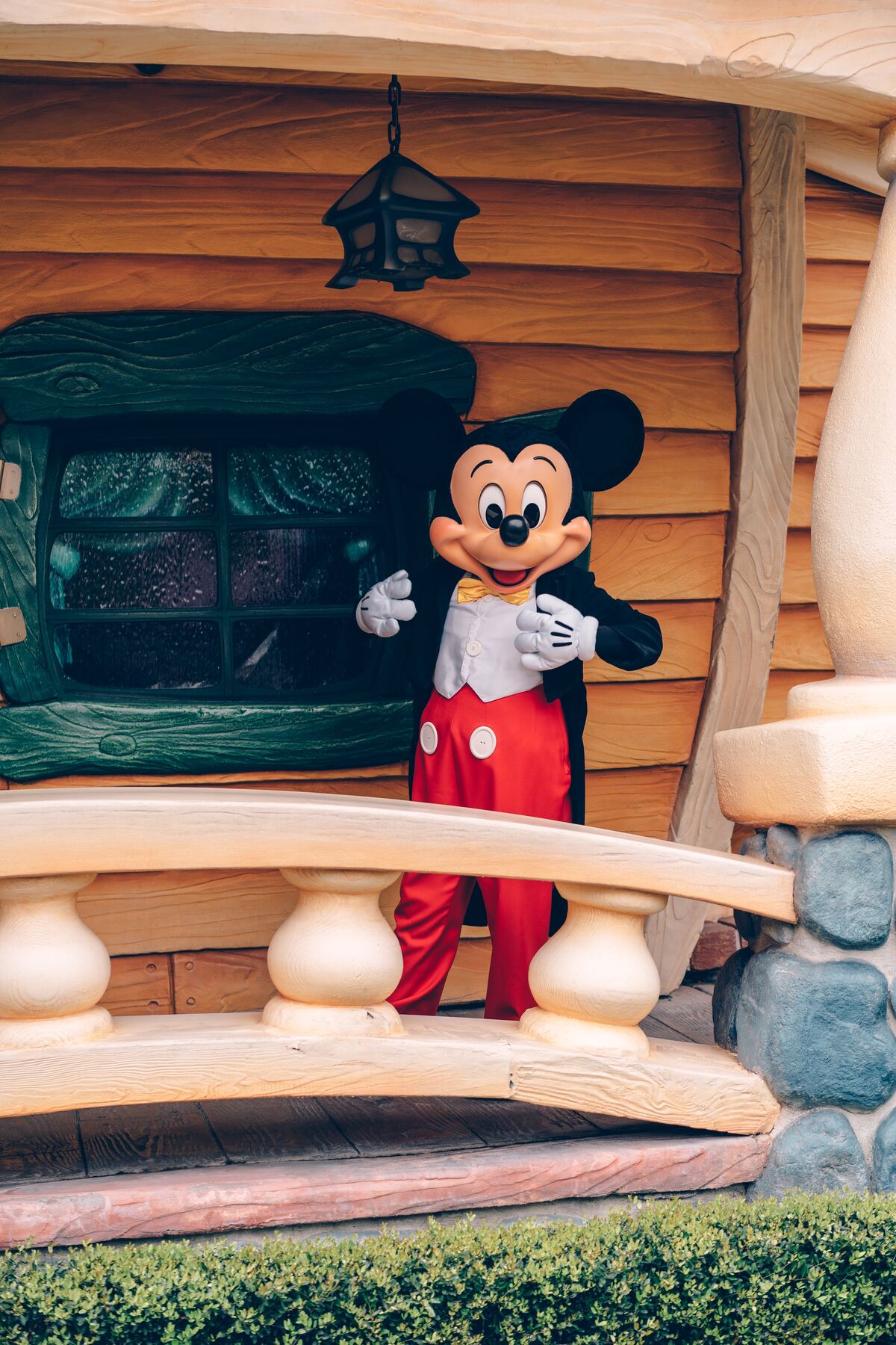 Mickey Mouse wearing a tuxedo as he gestures to himself with a smile
