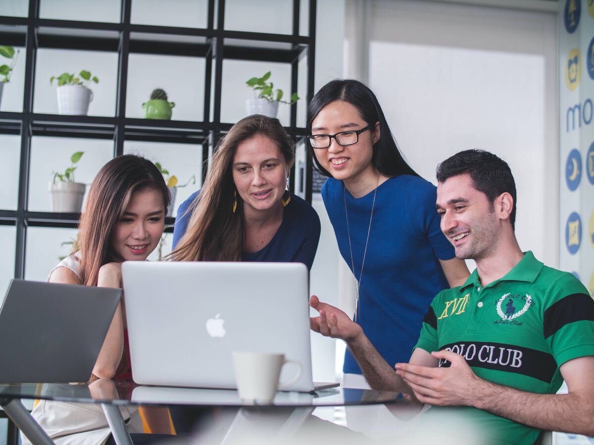 A group of people gather to discuss in front of a laptop