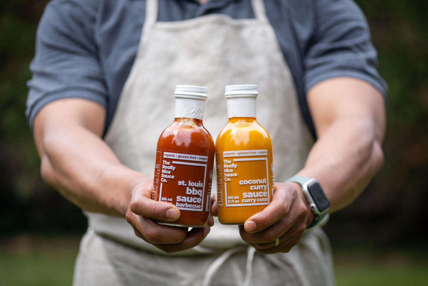 A man holds two bottles of BBQ and curry sauce