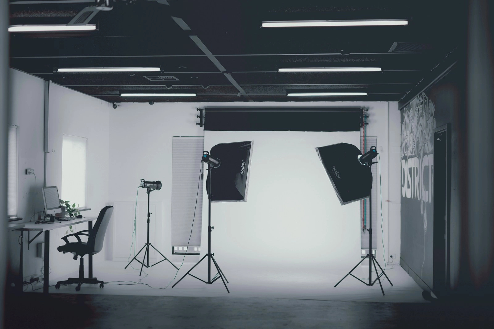 A photography studio with two light stands and a white backdrop