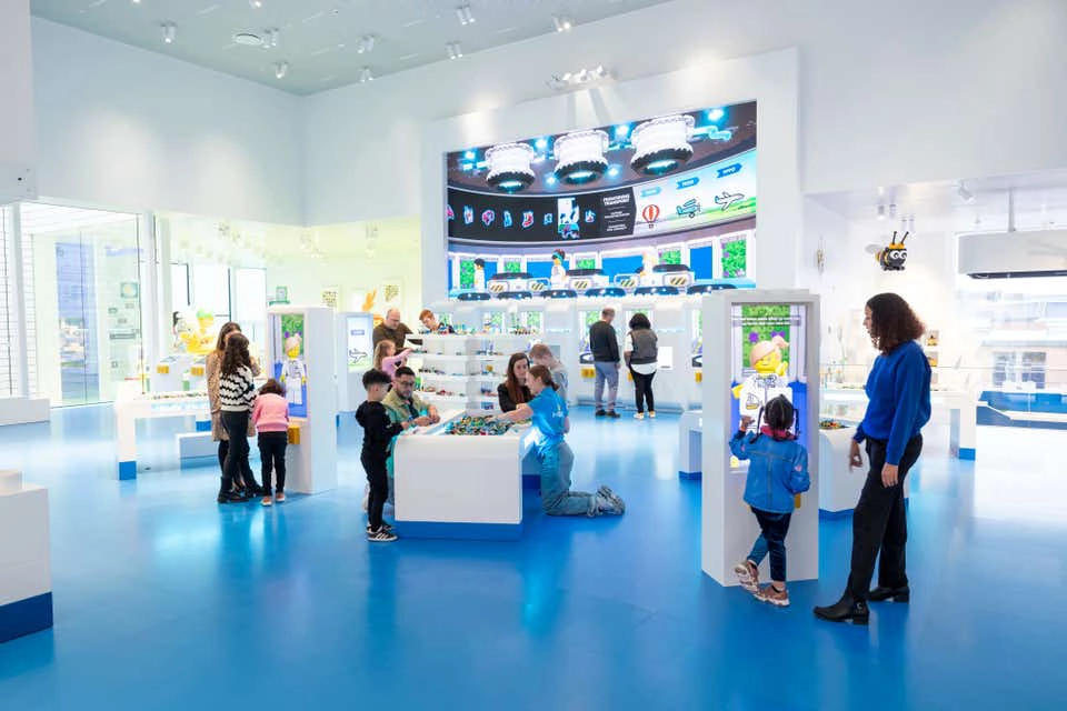 Parents and children playing with legos and digital displays in a blue and white creative studio