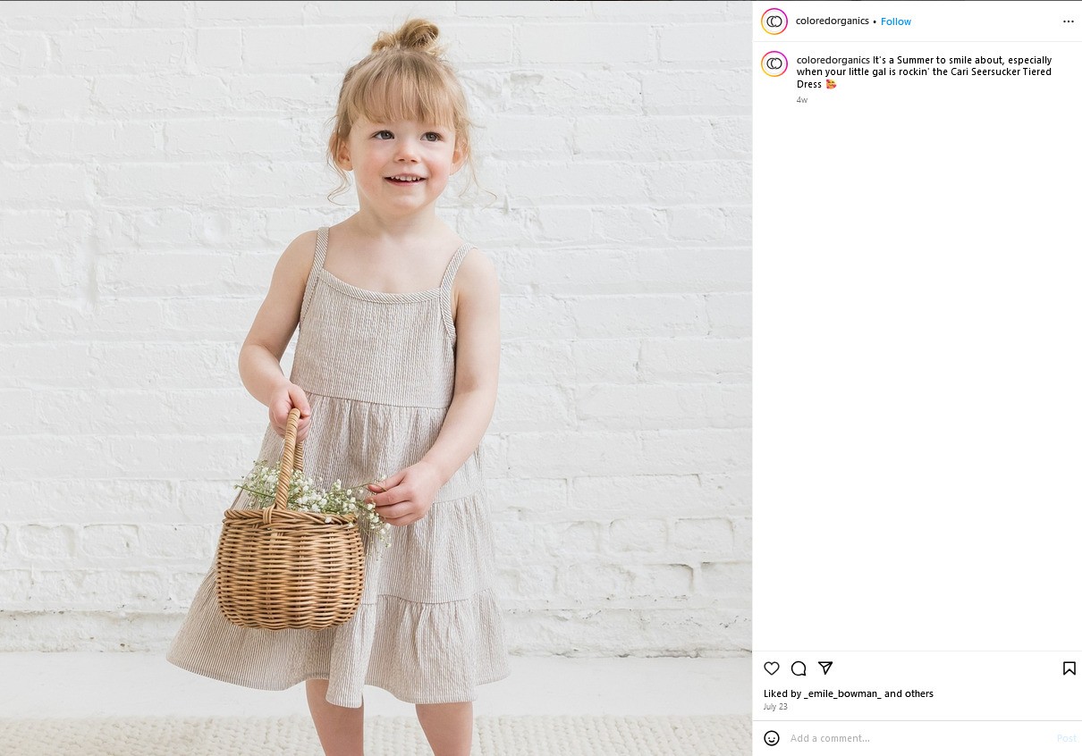 A girl in a linen dress holds a basket of flowers