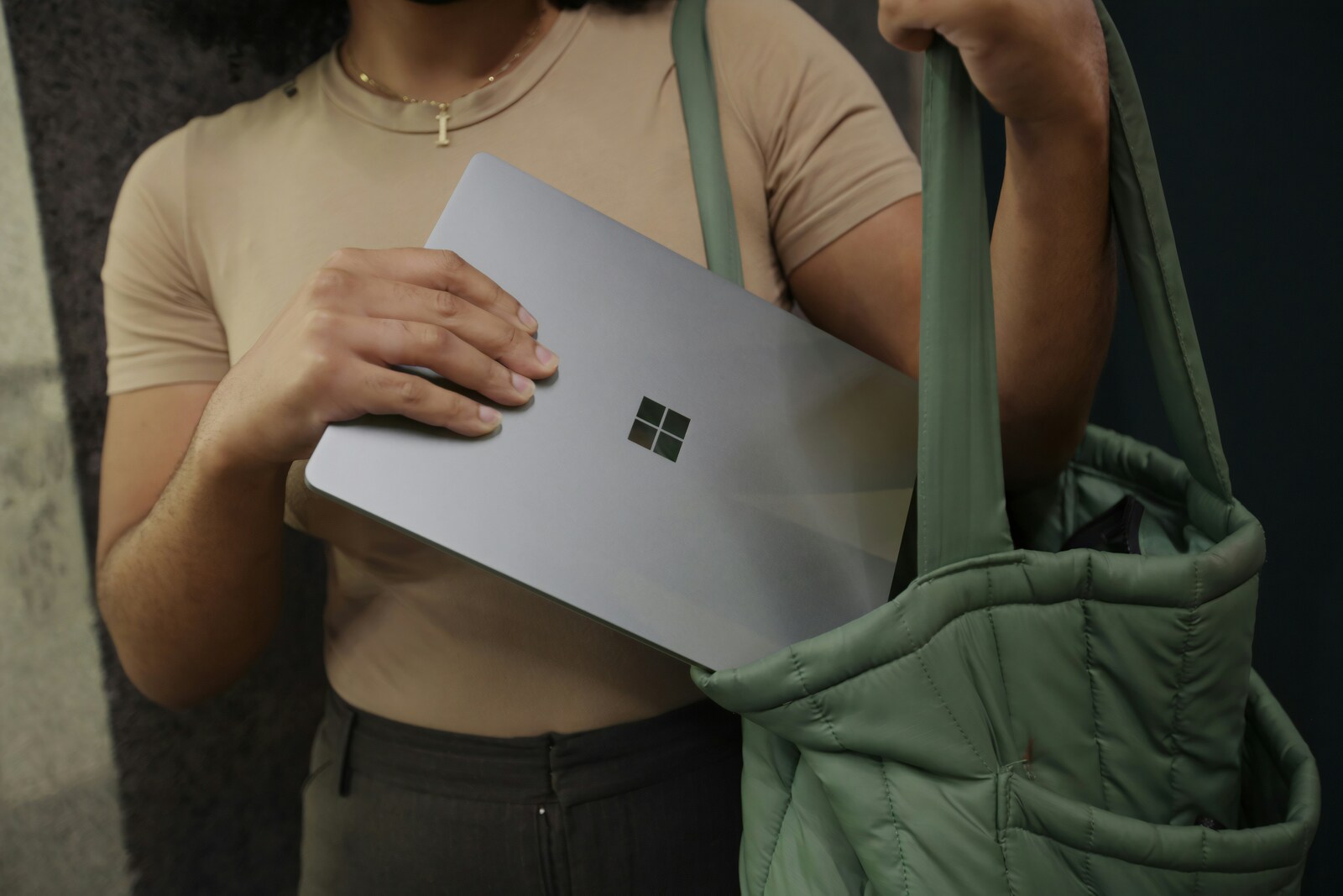 A lady puts a laptop in her green bag