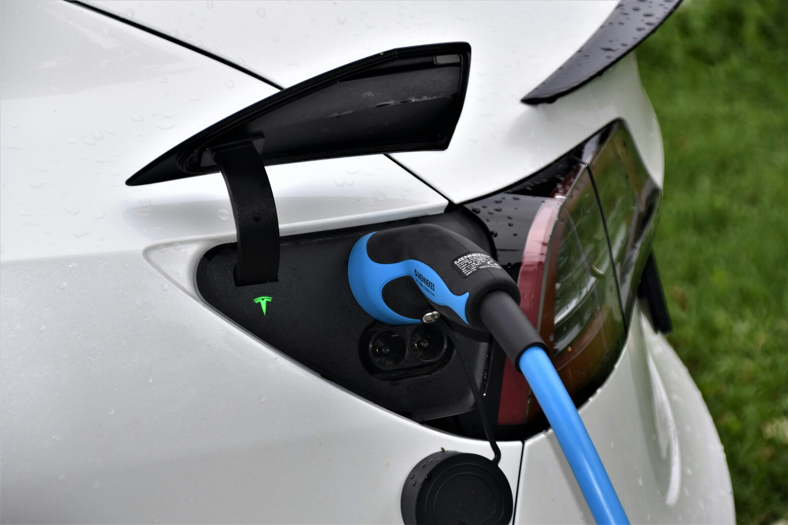 Rear part of a white car with a blue electronic charger