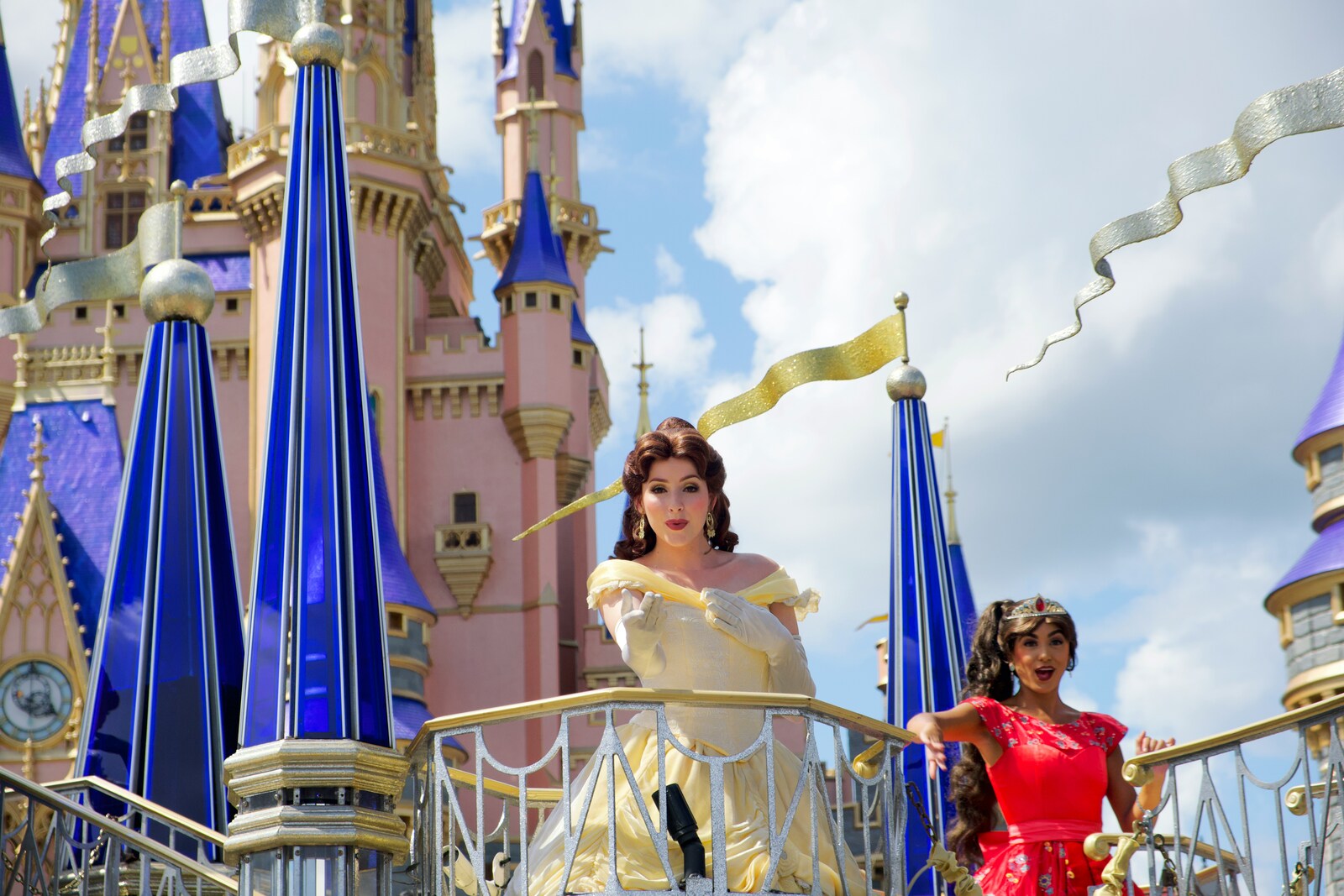 A woman dressed in a yellow gown extends her arm out