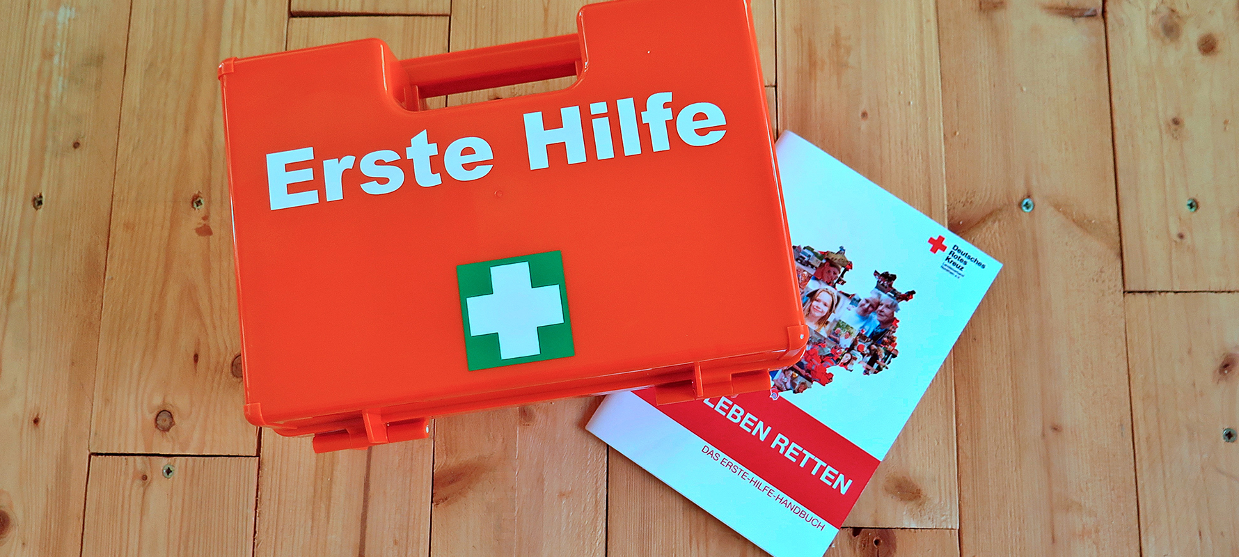 ErsteHilfe-Kasten, der auf Erste-Hilfe-Handbuch liegt.