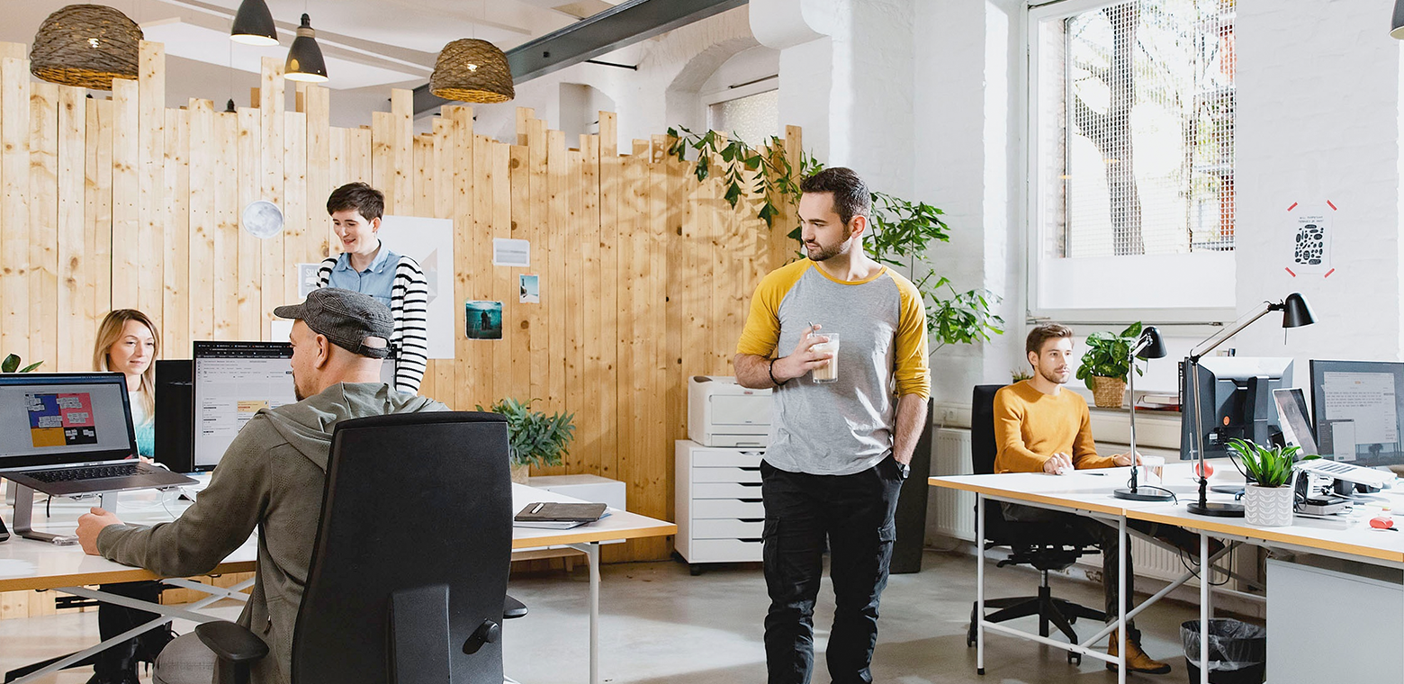 Szene aus dem brainbits Büro: Drei Personen sitzen am Tisch, zwei laufen herum.