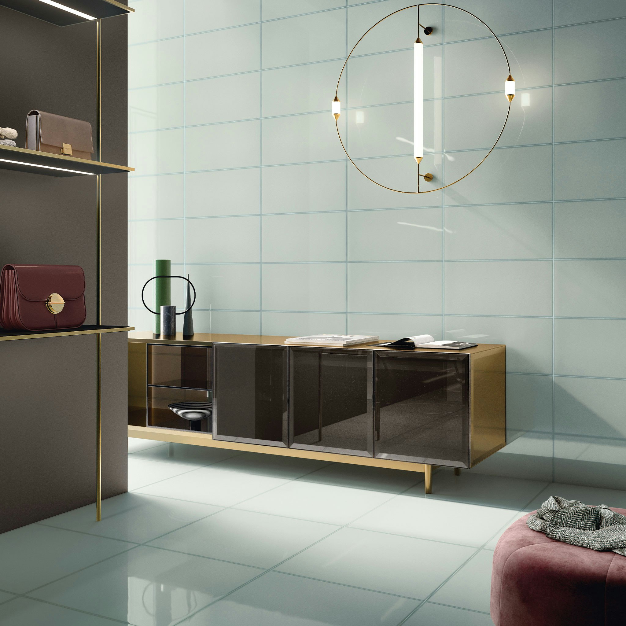 Glass-look light aqua coloured tiles on the floor and walls. Featuring a gold console table by the wall and a round modern pendant above it. Handbags are displayed on the left and a glimpse of a velvet ottoman can be seen on the bottom right.