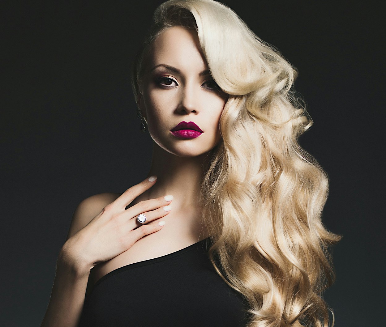 blond woman with long wavy hair and bright red lipstick posing