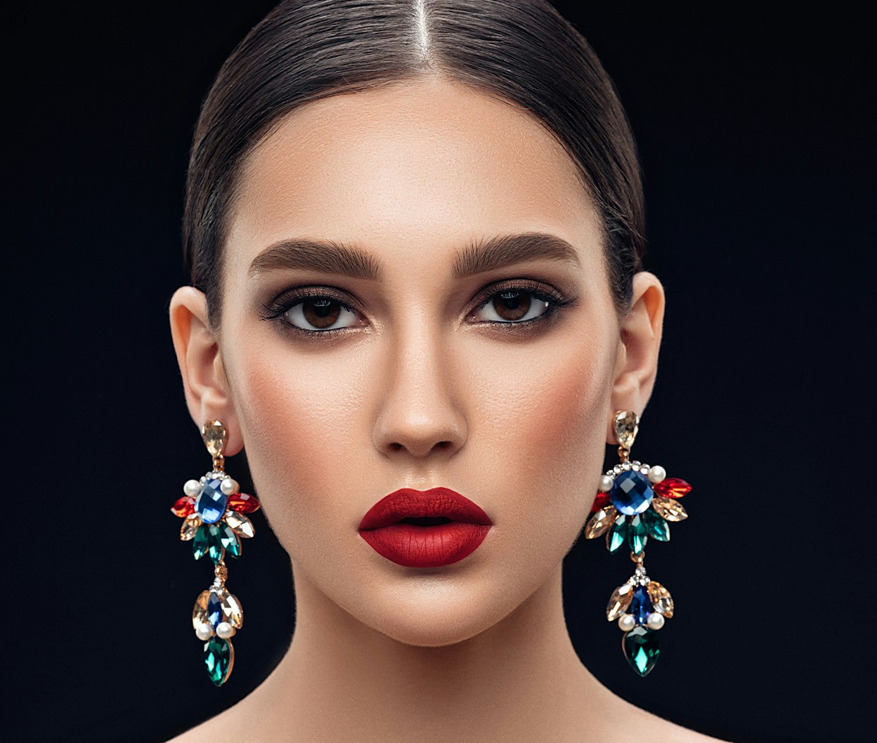 woman with red lipstick and earrings on a black background