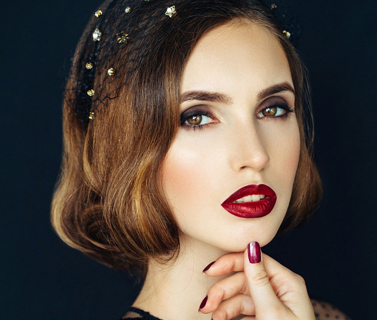 woman with red lipstick and a gold headpiece posing for a picture