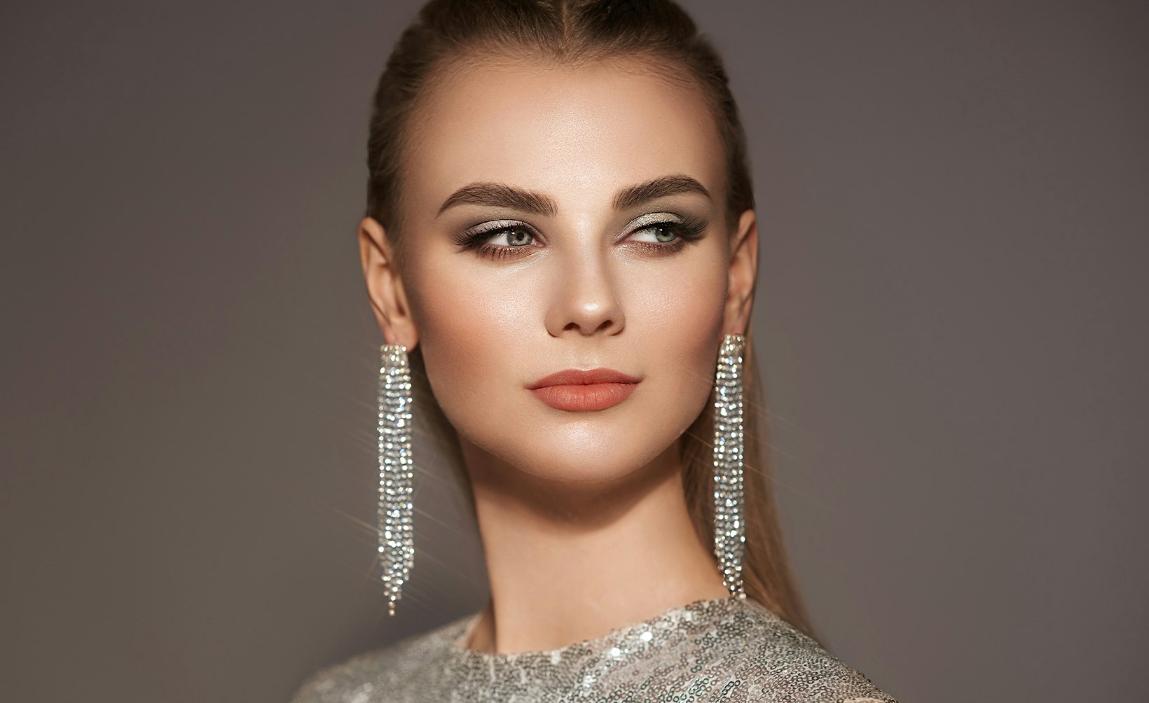 woman with long hair wearing silver dress and earrings