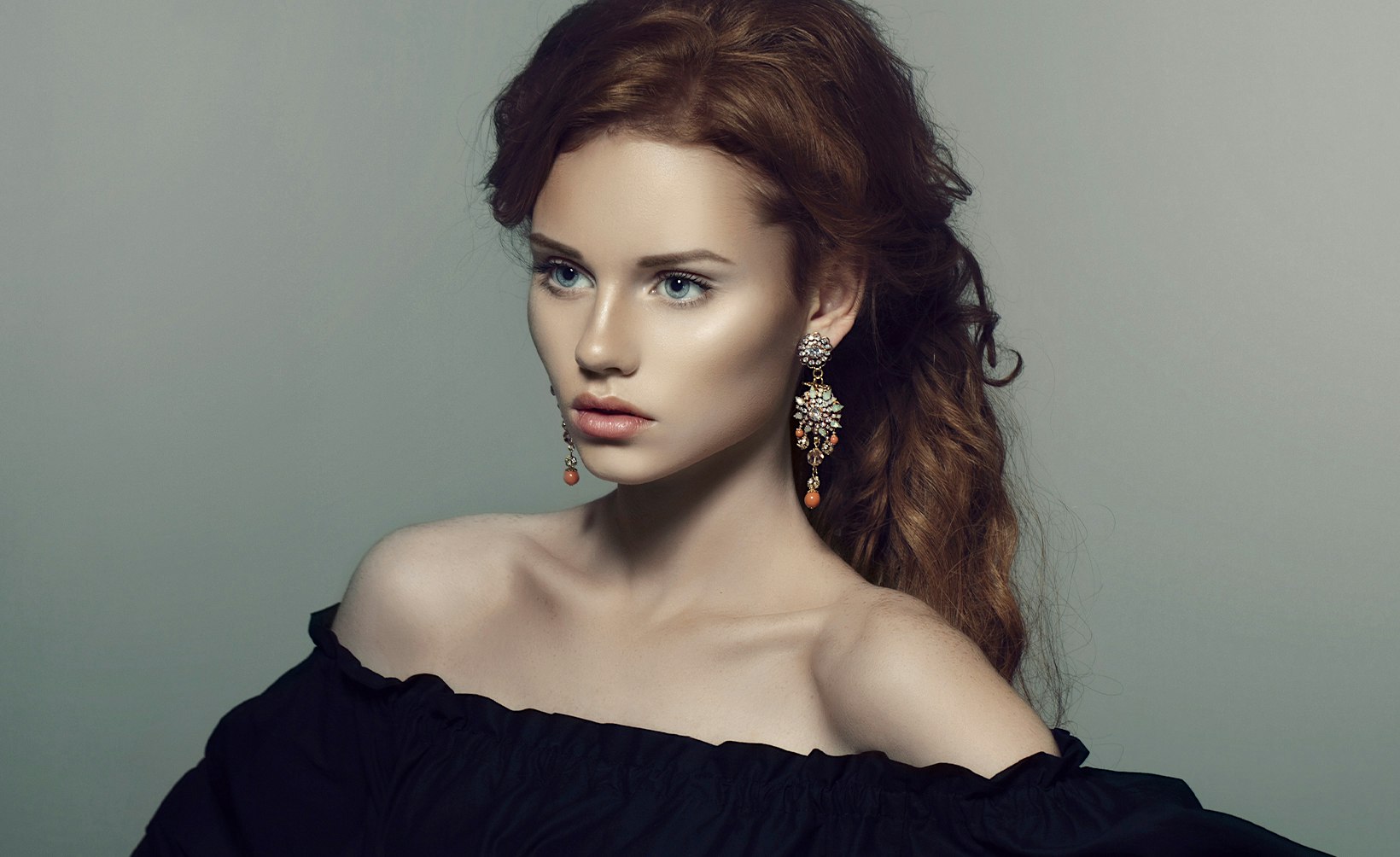 a woman with a black dress and earrings posing for a picture