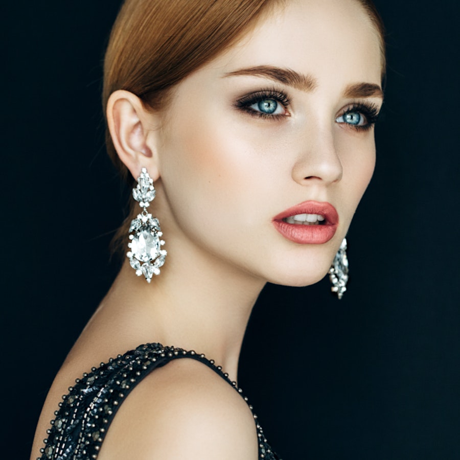 woman with a black dress and earrings posing for a picture