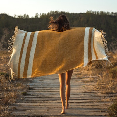 Donna che cammina in natura con coperta sulle spalle