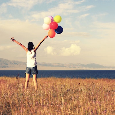Donna in riva al mare con palloncini colorati