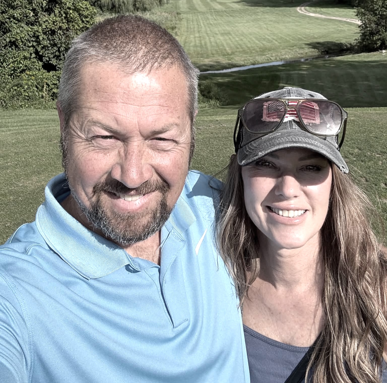 Me and Jason taking a selfie squinting into the sun with a golf course in the background