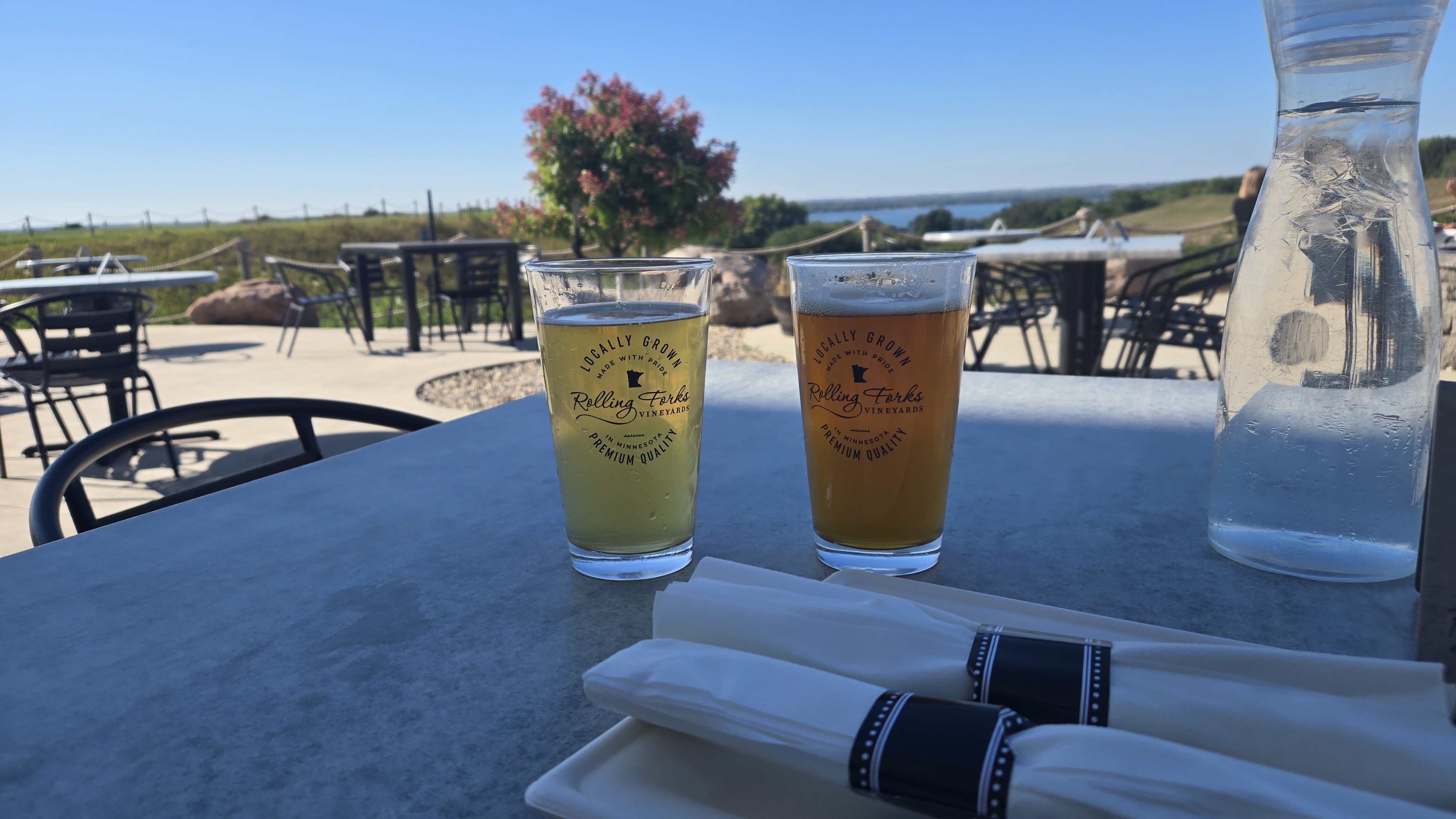 two beers on a table with a vineyard in the background