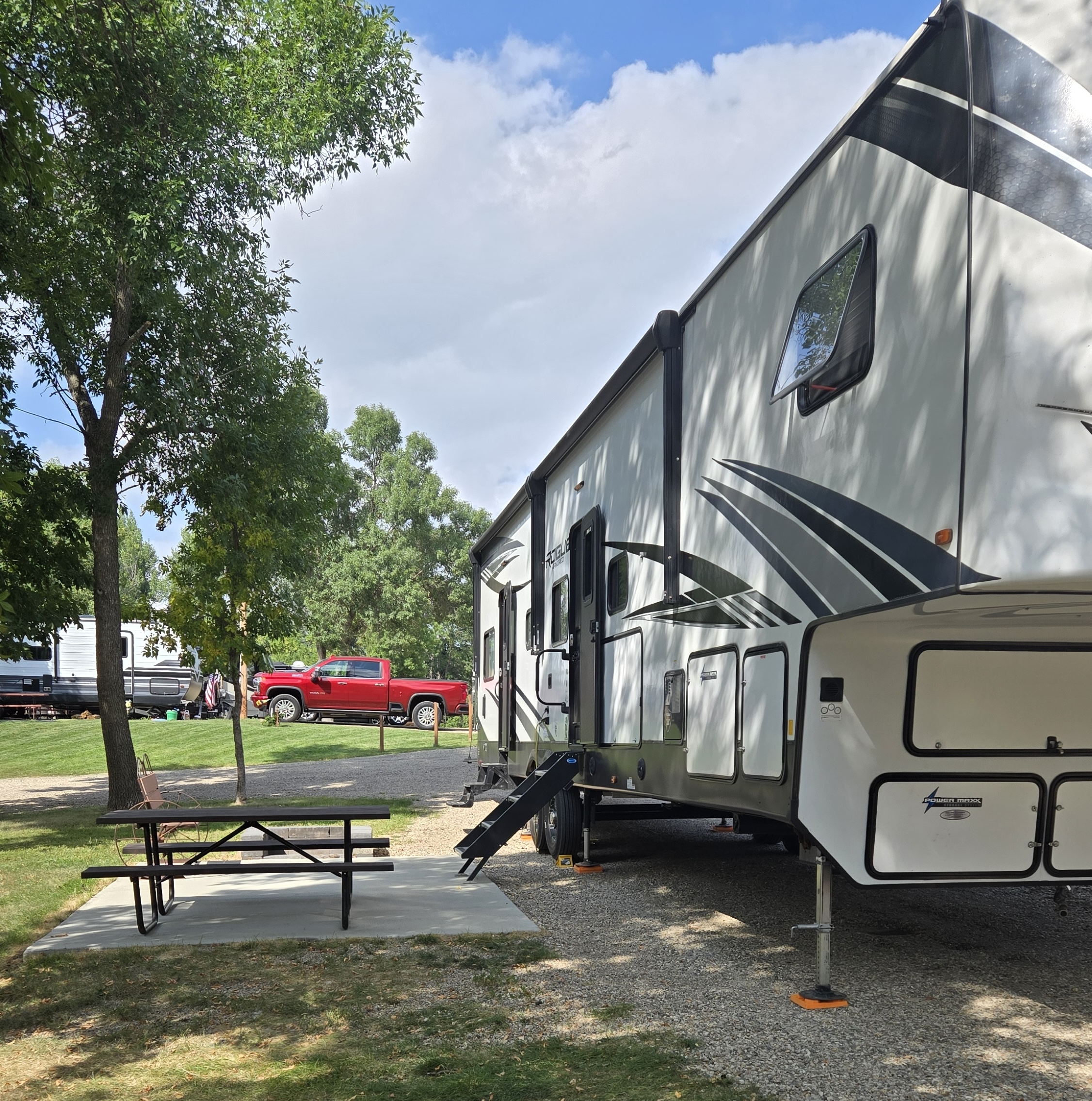 passenger side of camper parked in campground with patio and picnic table