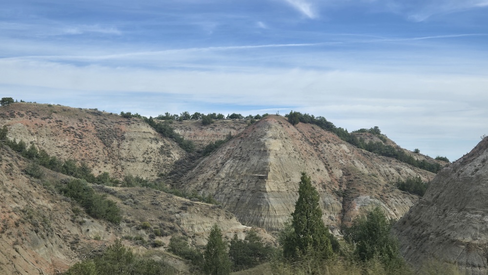 rocky hill and pillar formations with grey and red striations and scattered trees
