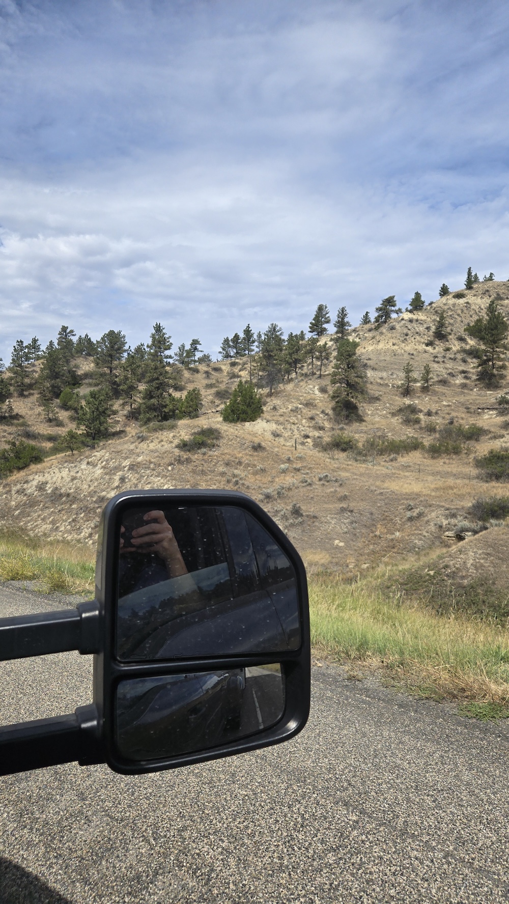 Montana hillside along highway taken from truck window with truck mirror in the foreground