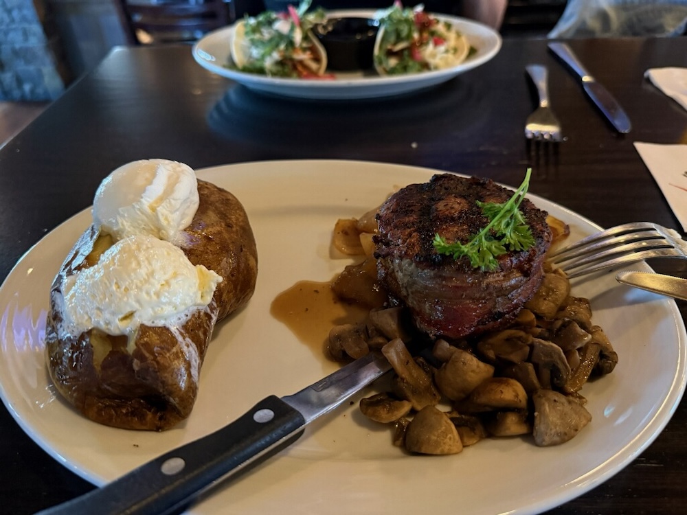 plated steak with mushrooms and side baked potato with sour cream and button
