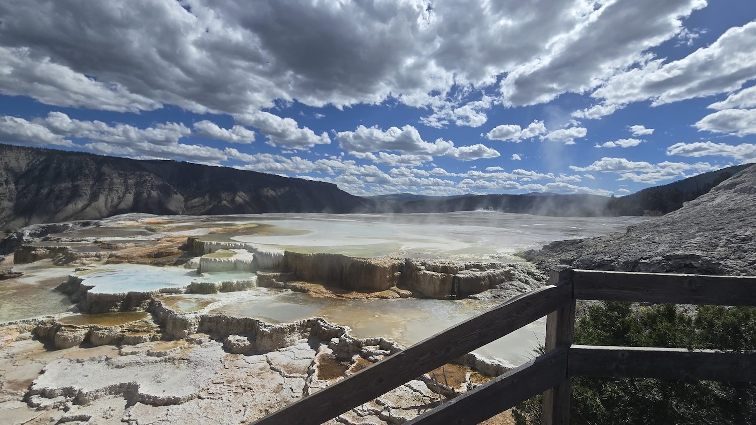 Mammoth Hot Springs with teal and amber pools of water and steam rising