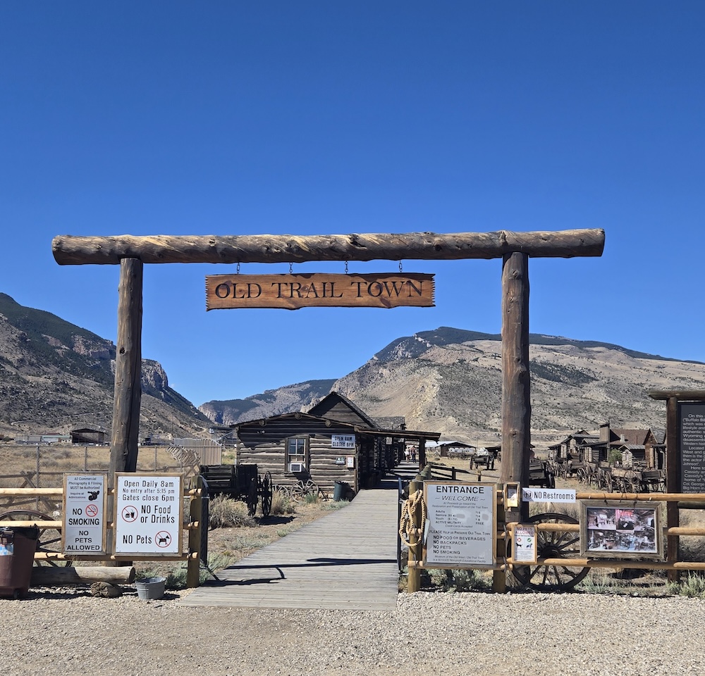 the entrance to old trail town with log post sign