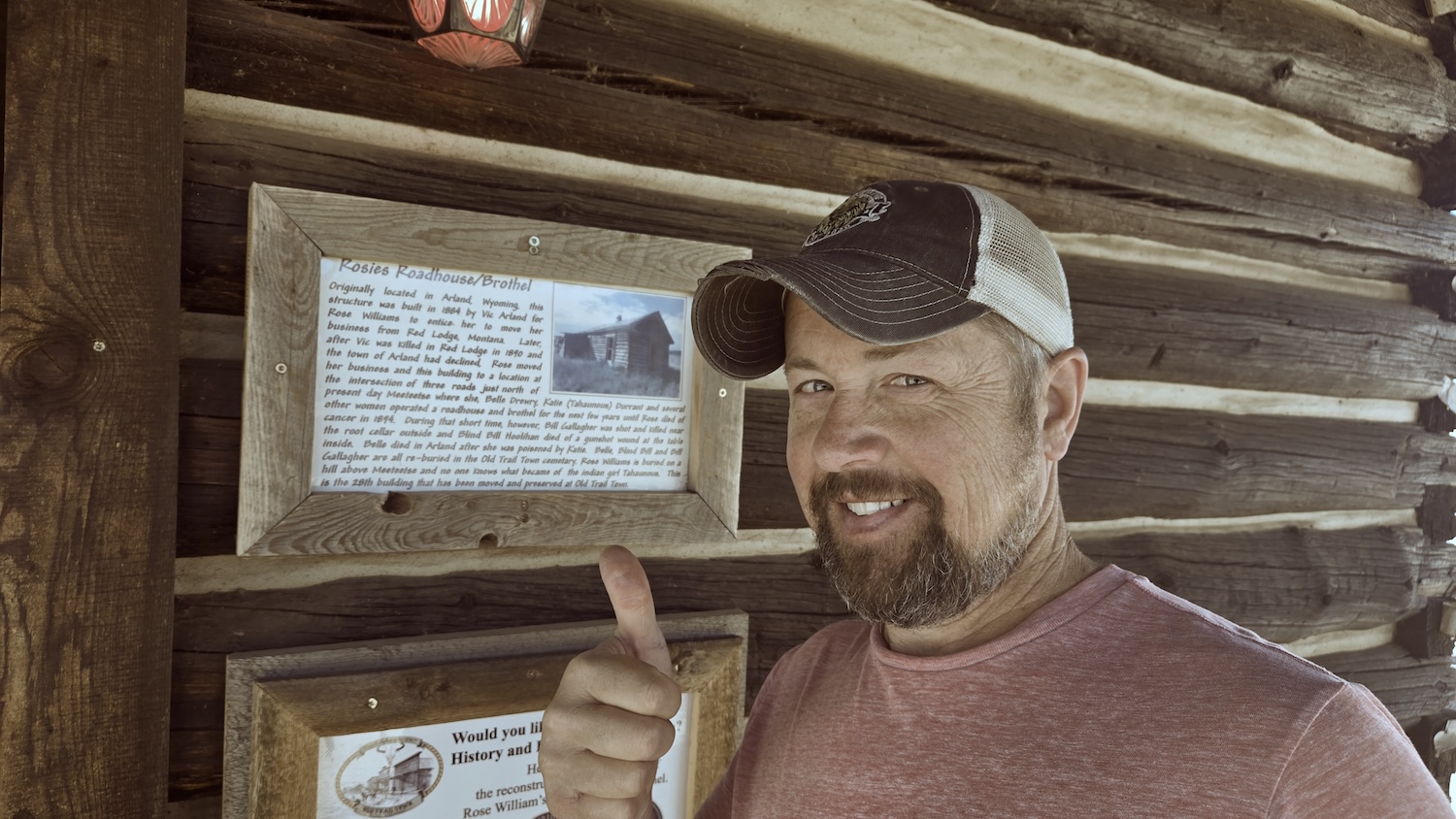 Jason smiling next to Rosie's Roadhouse and Brothel sign