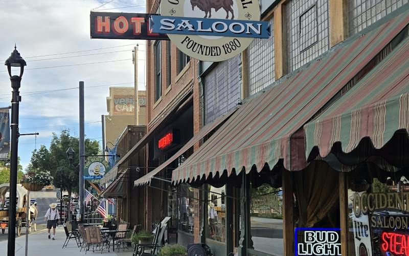 front of the Occidental Hotel in Buffalo, WY with saloon sign and metal tables along the sidewalk