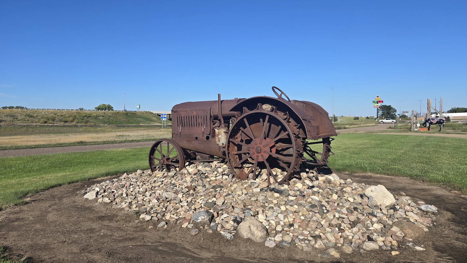 old an rusted metal tractor sitting on pile of stones