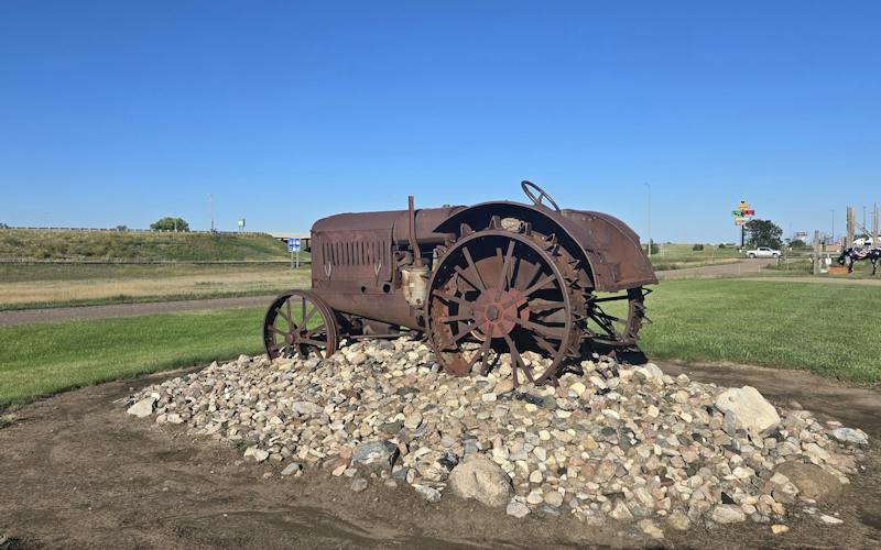 old an rusted metal tractor sitting on pile of stones