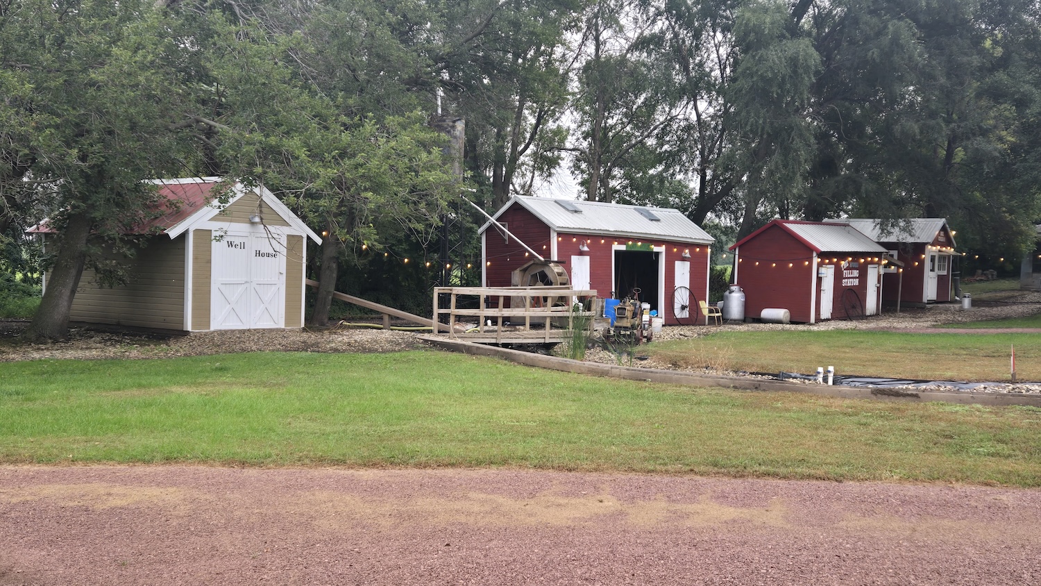 several small buildings set up to look like a tiny town with gas station, well house and bridge over a small stream
