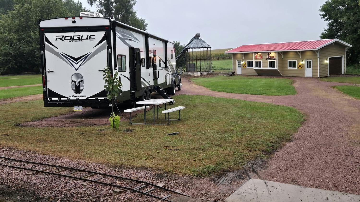 camper parked in small campground with miniature train tracks and outbuildings