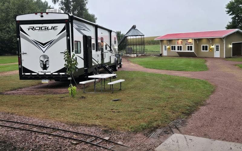 camper parked in small campground with miniature train tracks and outbuildings