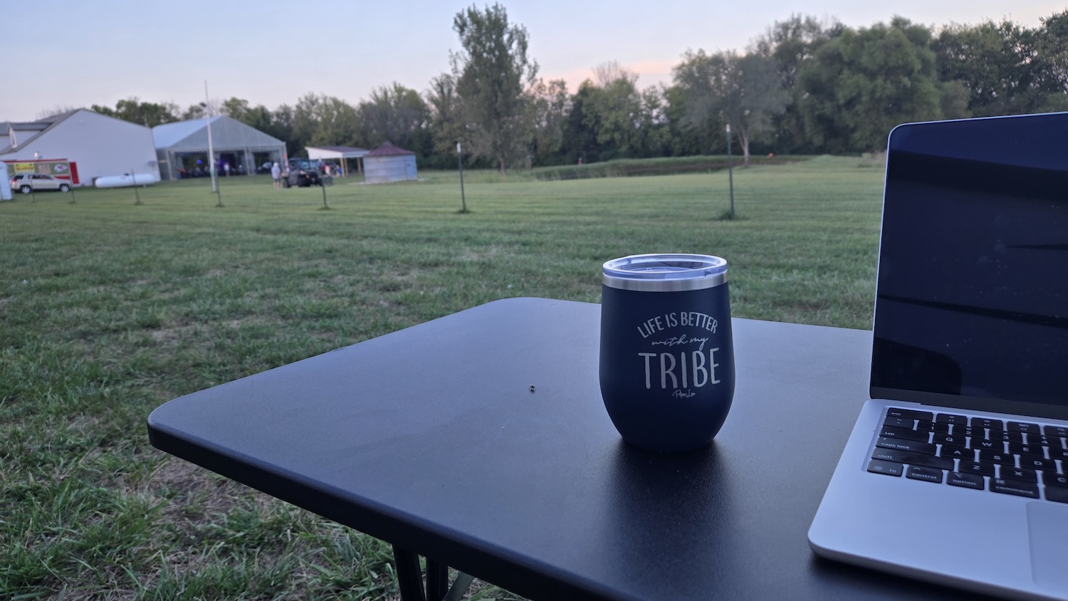 Wine glass on black laminate table with laptop, wine glass says life is better with my tribe