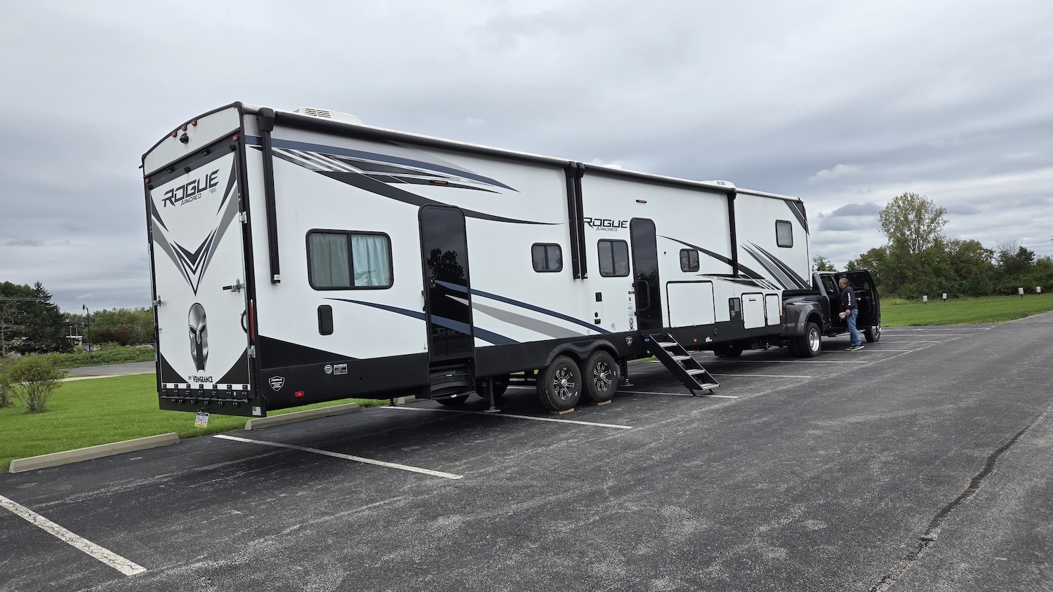 camper and truck parked in a parking lot with grassy area behind