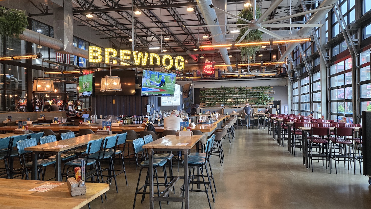 the inside taproom at Brewdog with rows of pub tables and yellow Brewdog sign