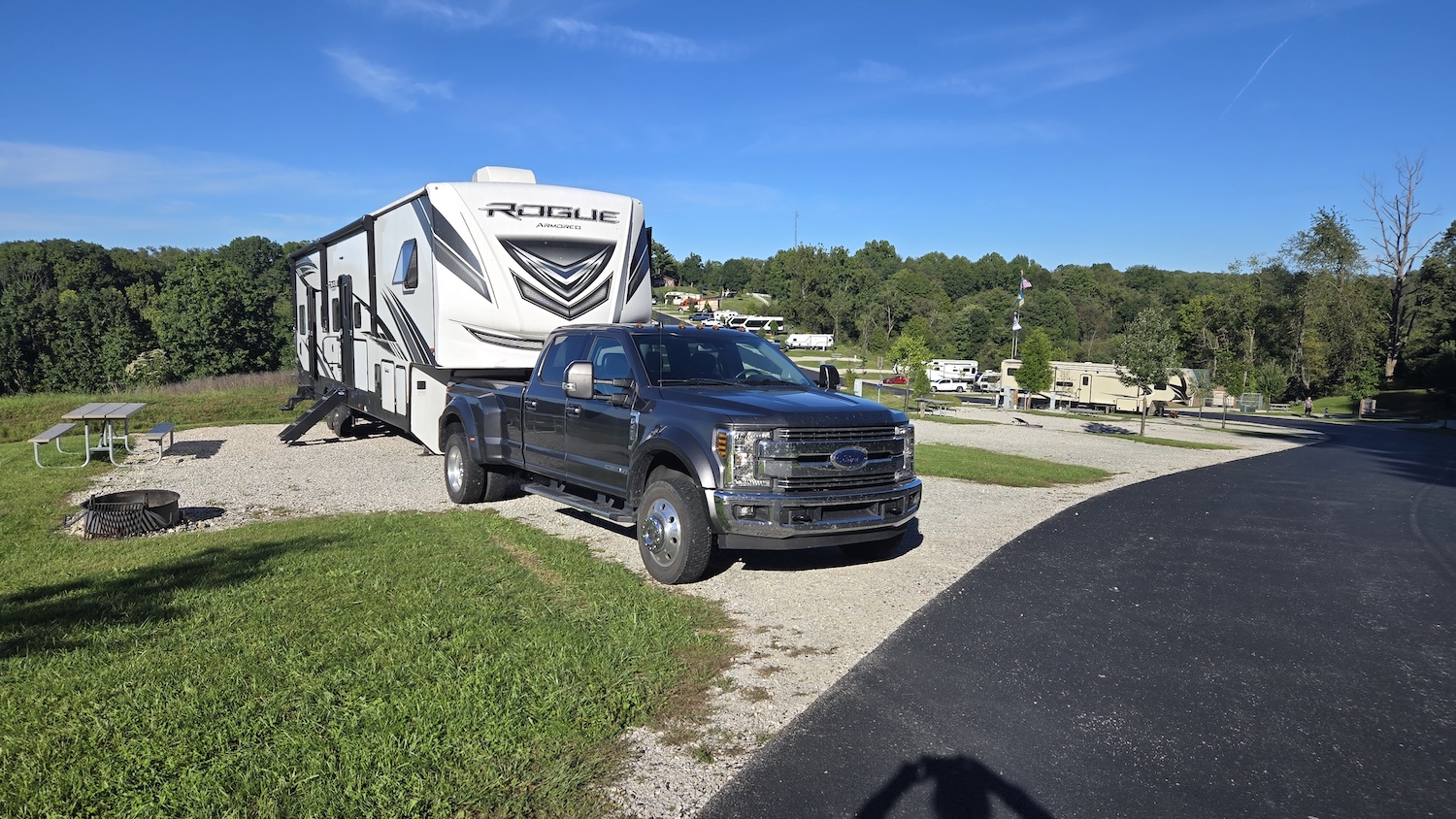 truck and camper parked in campground with gravel site and green grassy area picnic table and firepit