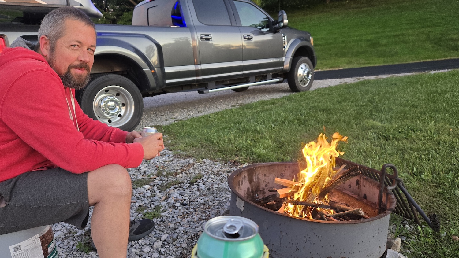 Jason sitting on a bucket admiring the fire he made in the firepit