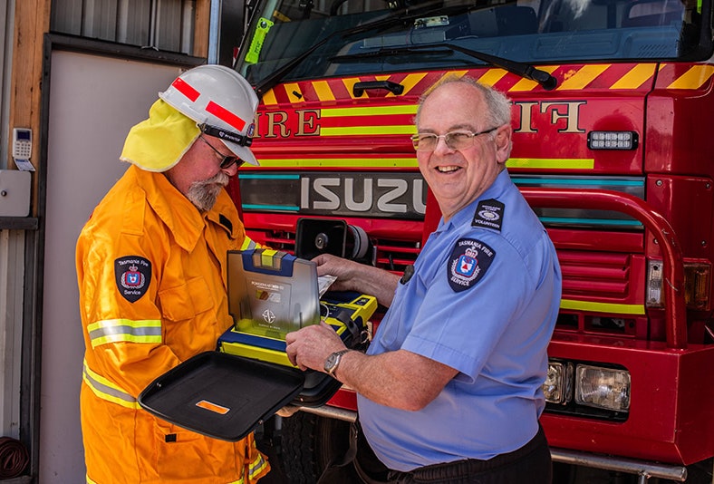 Two fire fighters looking at a defibrillator