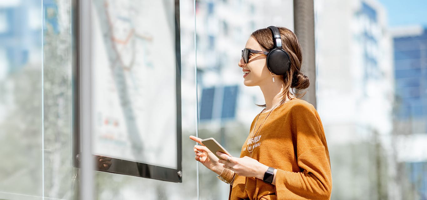 Woman wearing earphones and holding a mobile phone