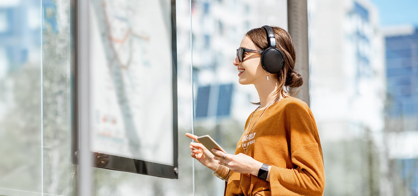 Woman wearing earphones and holding a mobile phone